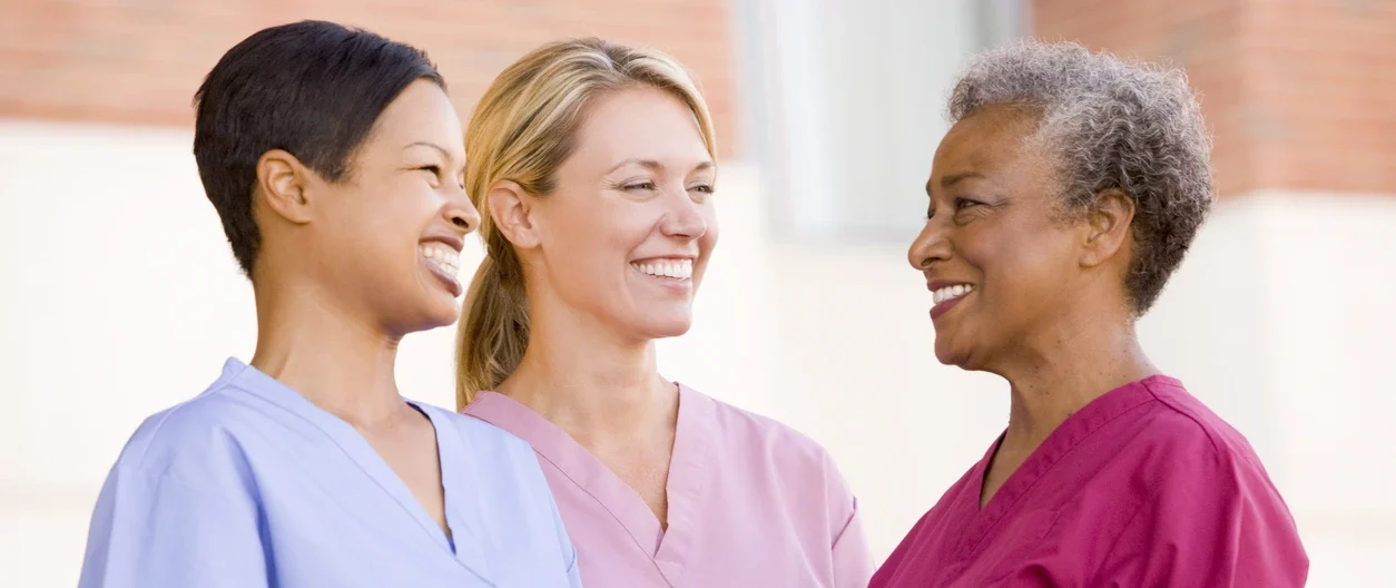 Three diverse nurses in scrubs smiling