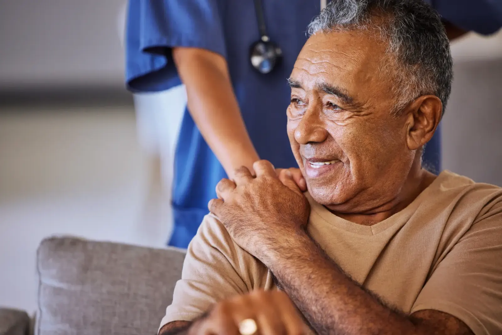 Elderly man holding a nurses hand on his shoulder