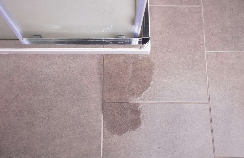 Water spilled on the bathroom floor near the window.