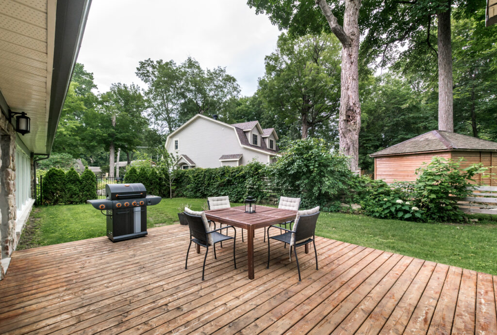 A home patio with a grill, wooden table, and metal chairs