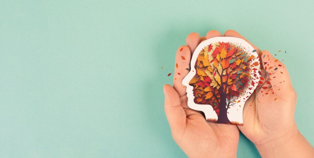 A pair of hands holds a paper head in the shape of a tree.