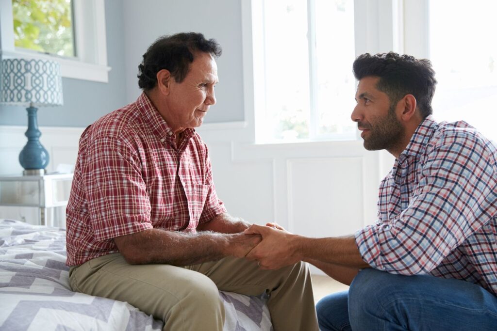 Adult son comforting his father with dementia.