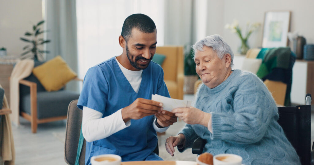 A caregiver with a senior woman in retirement, looking at photographs in a furnished room.