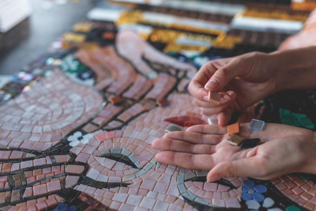 An artist places mosaic tiles in a pattern in the shape of a face.